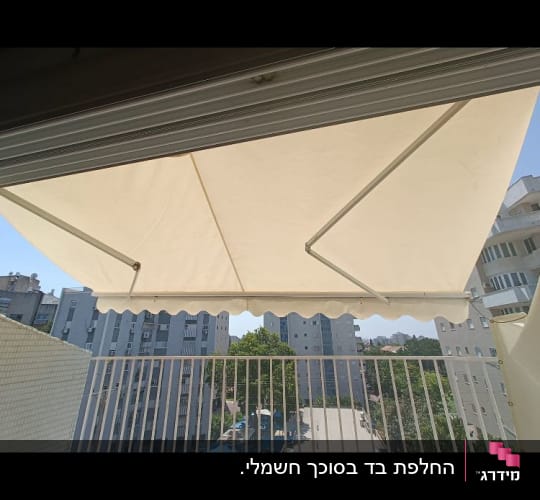 סוכך זרועות מתקפל בצבע קרם המותקן במרפסת שמש